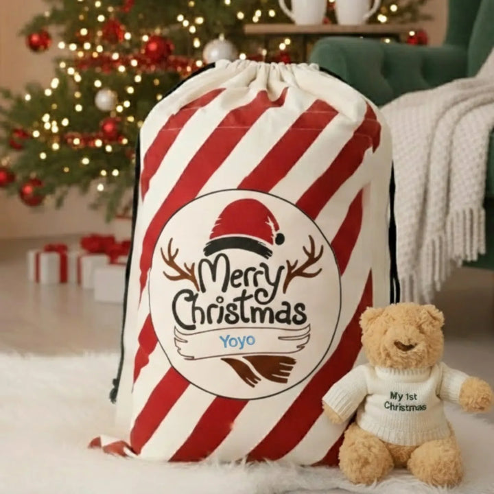 Red and white striped Christmas sack with 'Merry Christmas' text, next to a teddy bear in a festive setting.
