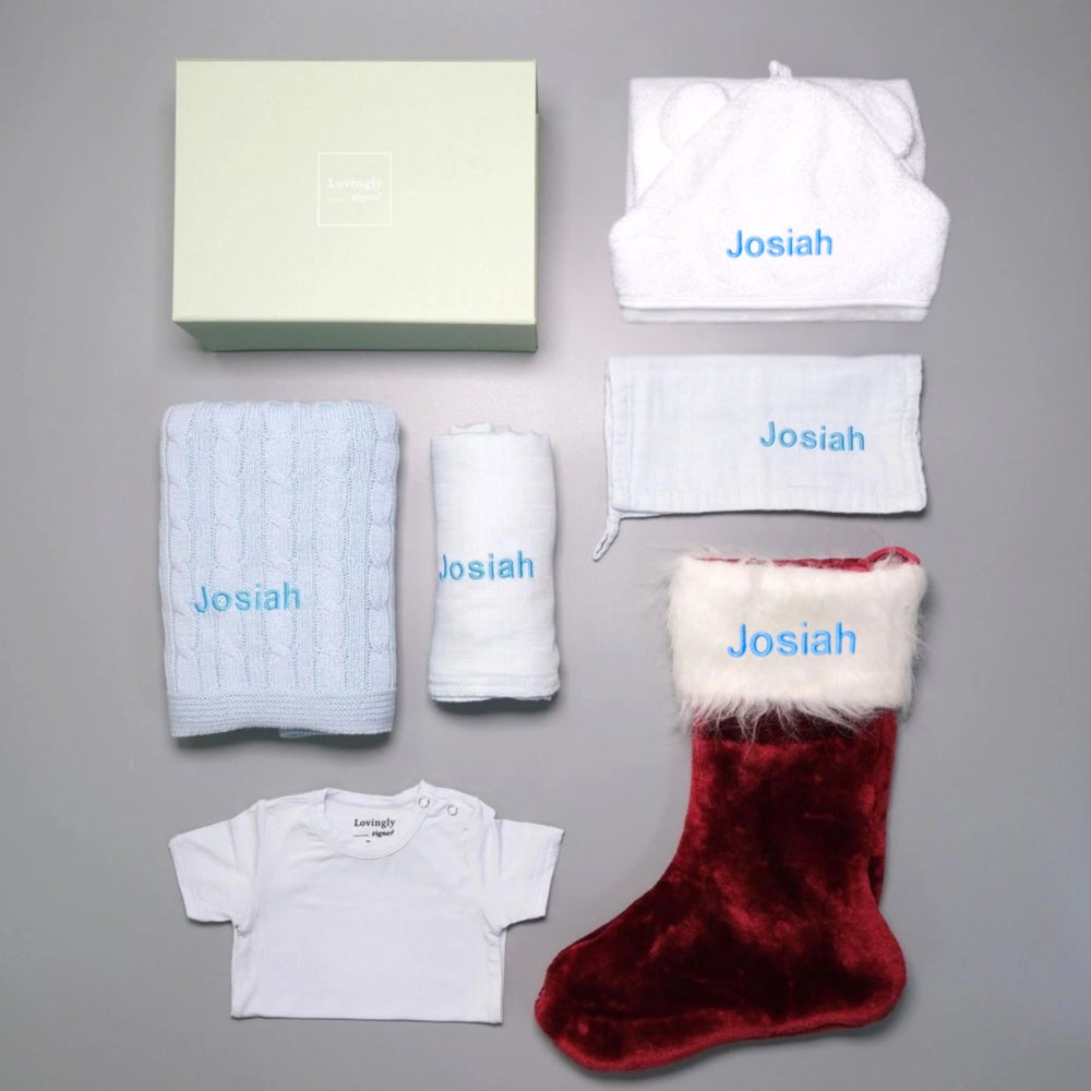 Christmas themed gift set in Blue consisting of hooded towel, muslin cloth, swaddle, cable knit blanket, Christmas edition babygrow and red stocking