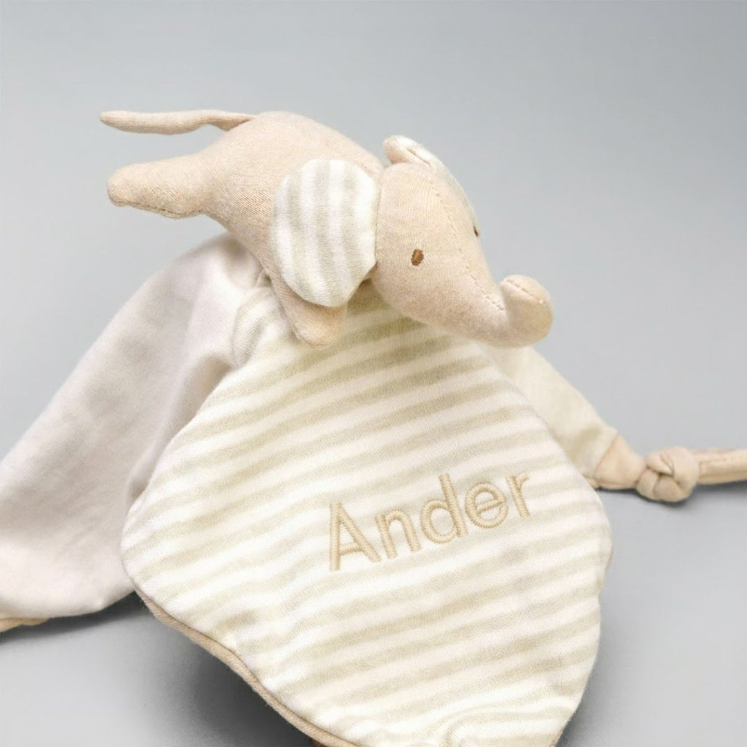 Beige elephant toy with 'Ander' embroidered on it against a gray background