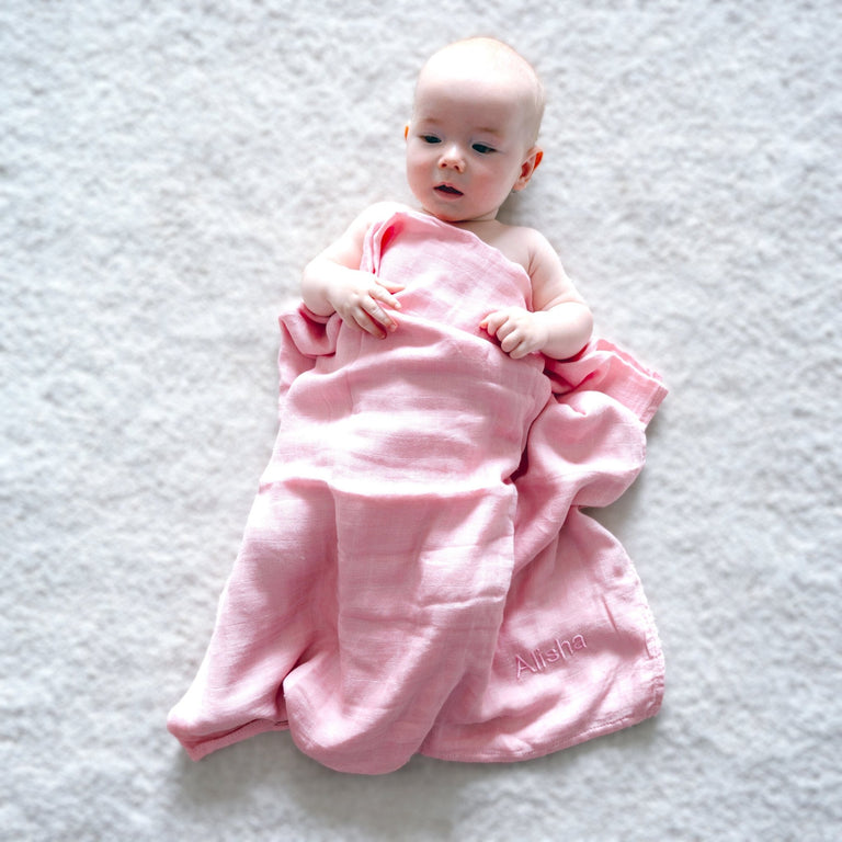 Baby covered with Pink Bamboo Muslin Swaddle with "Alisha" personalised in Pink Thread