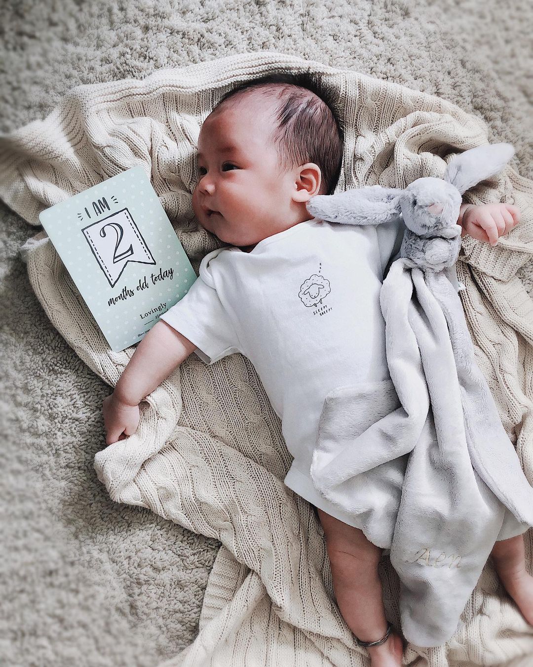 Baby holding a Jellycat bunny comforter 
