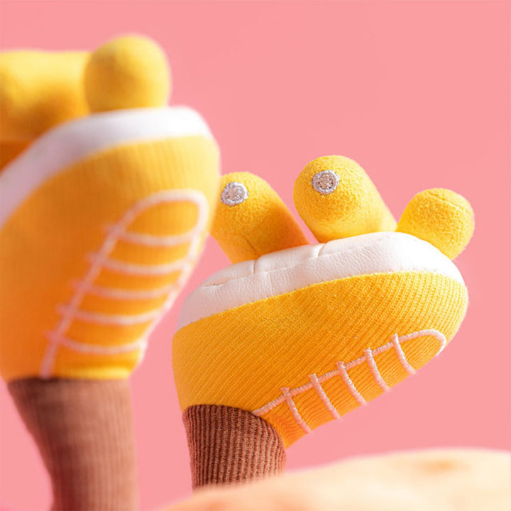Close-up of the yellow roller skates on the soft toy, showing white detailing, embroidered laces and small plush wheels against a pink background.