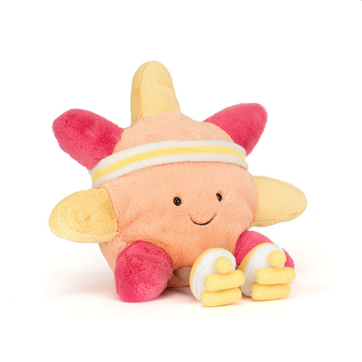 Front view of the smiling peach and yellow roller-skating sun soft toy wearing a white and yellow sweatband, with bright pink limbs and yellow roller skates.