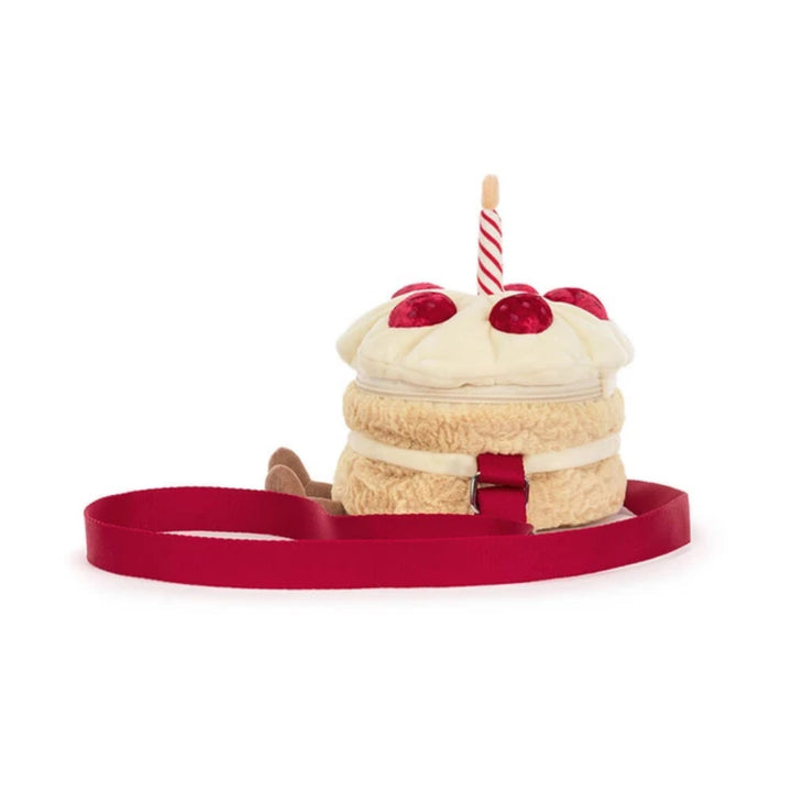 Back view of the birthday cake crossbody bag showing the cream frosting, red berry details, striped candle and adjustable red shoulder strap.