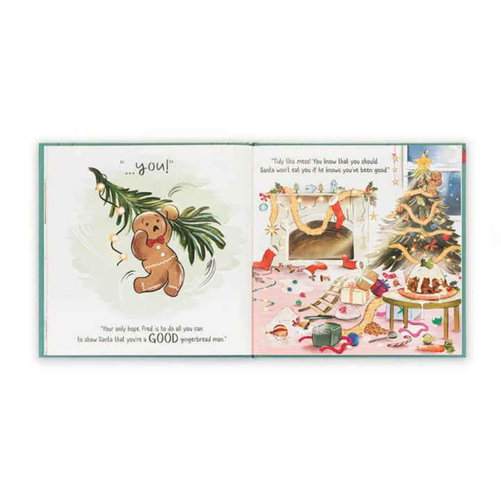 Open “Gingerbread Fred” children’s Christmas book showing a gingerbread character beside a messy festive living room with a decorated Christmas tree.