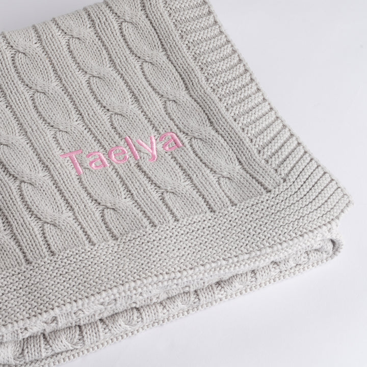 Grey Cable Knit Blanket 
with "Taelya" personalised in pink thread