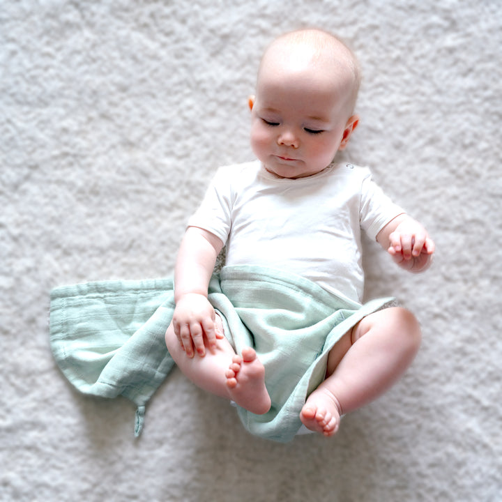 baby covered in green wash cloth 