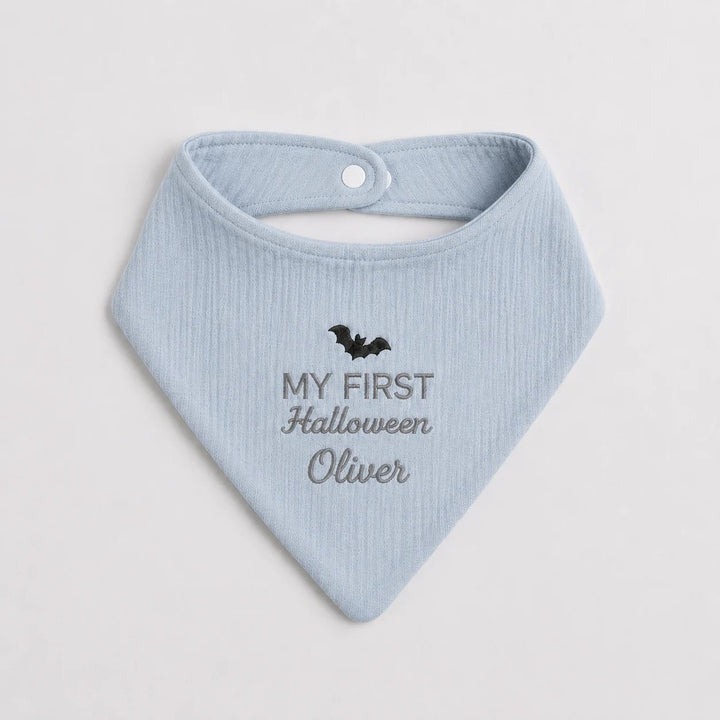 Light blue baby bib with 'My First Halloween Oliver' text and bat design on a light gray background
