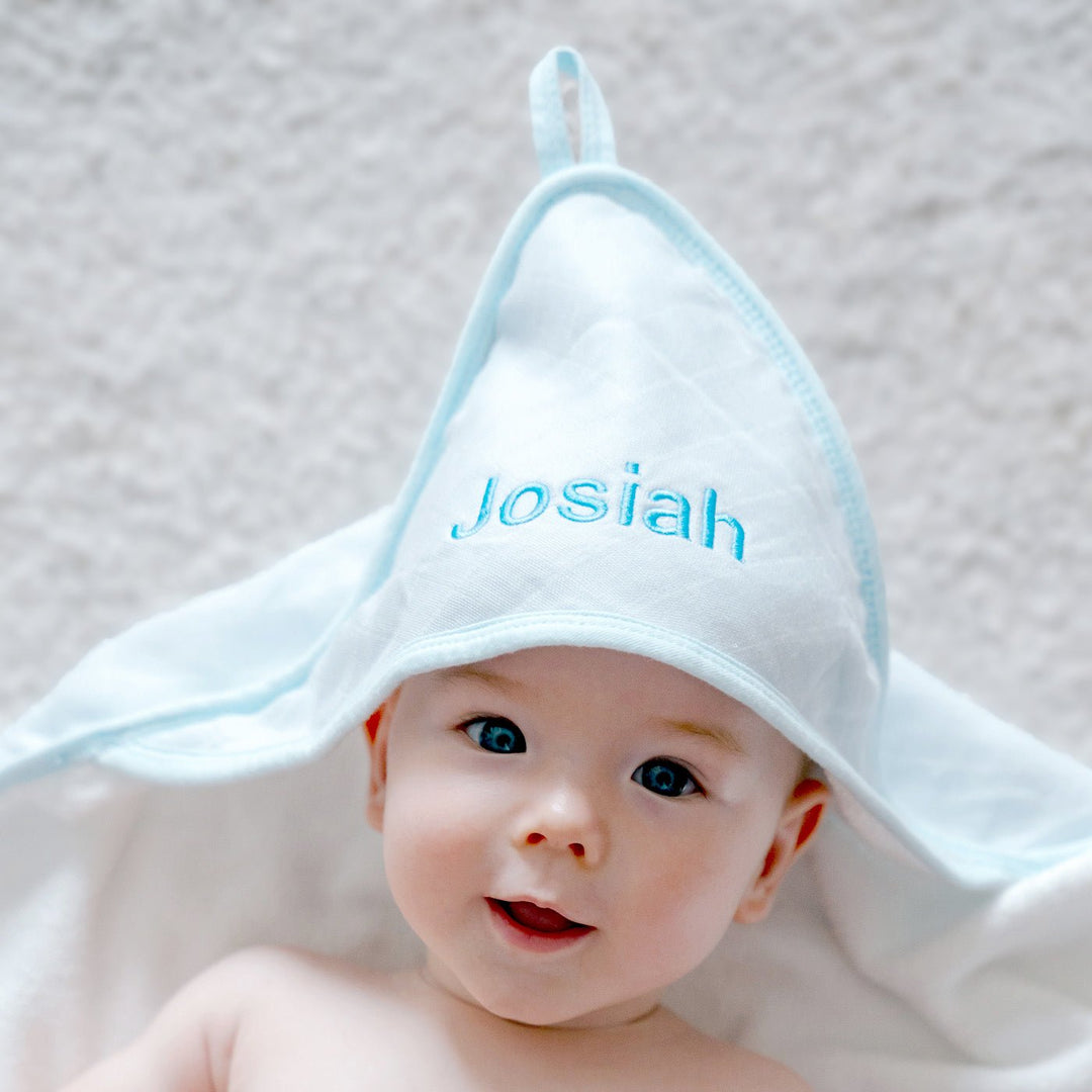  baby is wearing a light blue hooded towel with the name "Josiah" embroidered on it.