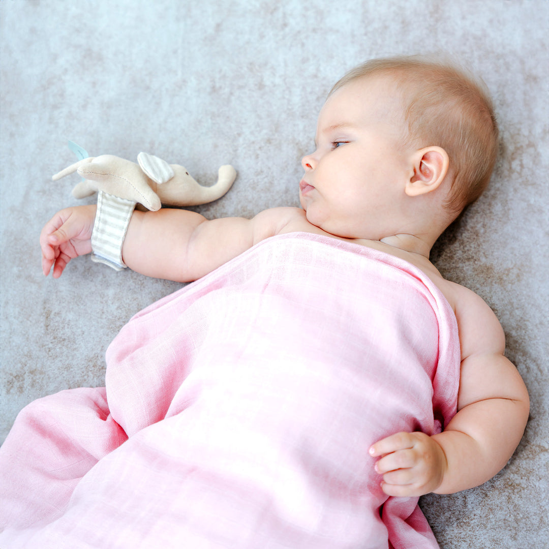 Baby sleeping with pink blanket and elephant toy
