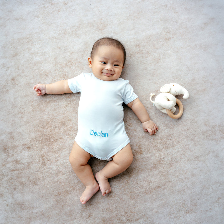 Smiling baby in personalized onesie with toy