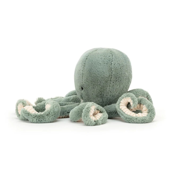 Sage green octopus plush viewed from the side, showing its soft rounded body, curled tentacles and cream textured detailing underneath.