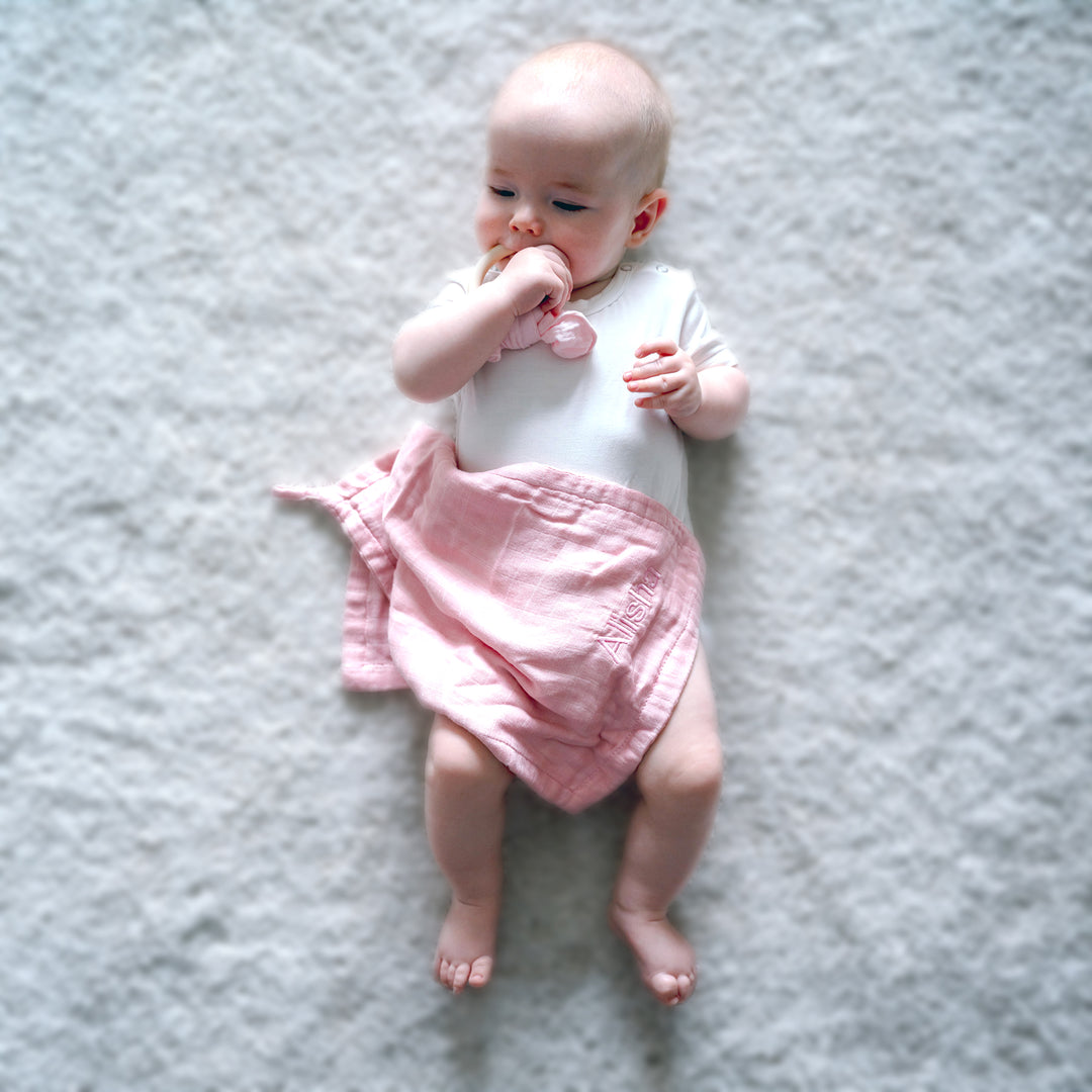 baby covered in Pink wash towel 