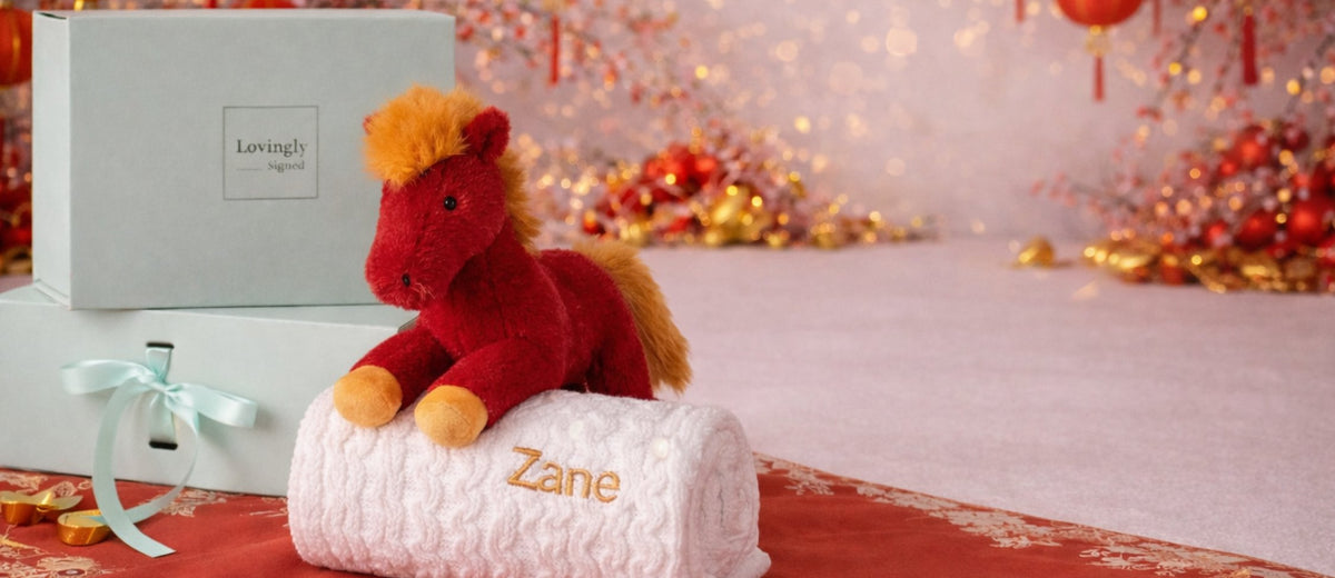 Red plush Jellycat horse toy  on a white personalised  blanket with a blurred Chinese new year festive background.