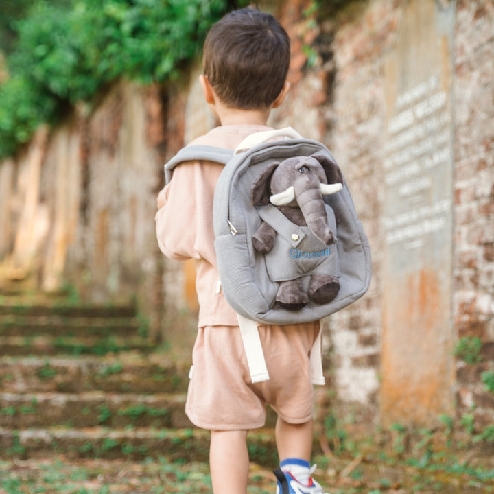 Toddler carrying elephant backpack with "Giovanni" personalised in blue thread