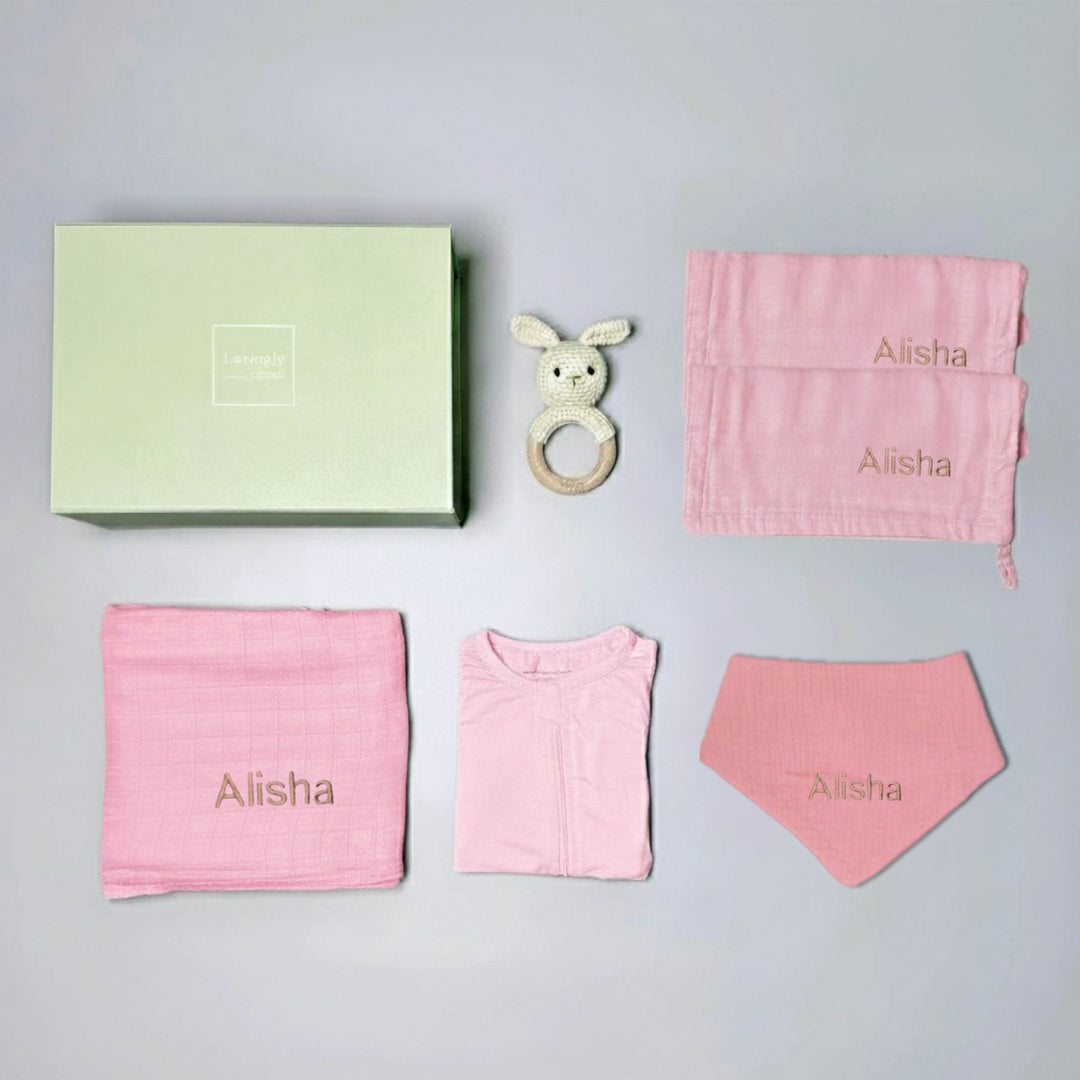 Baby gift set with pink items and a green box on a gray background