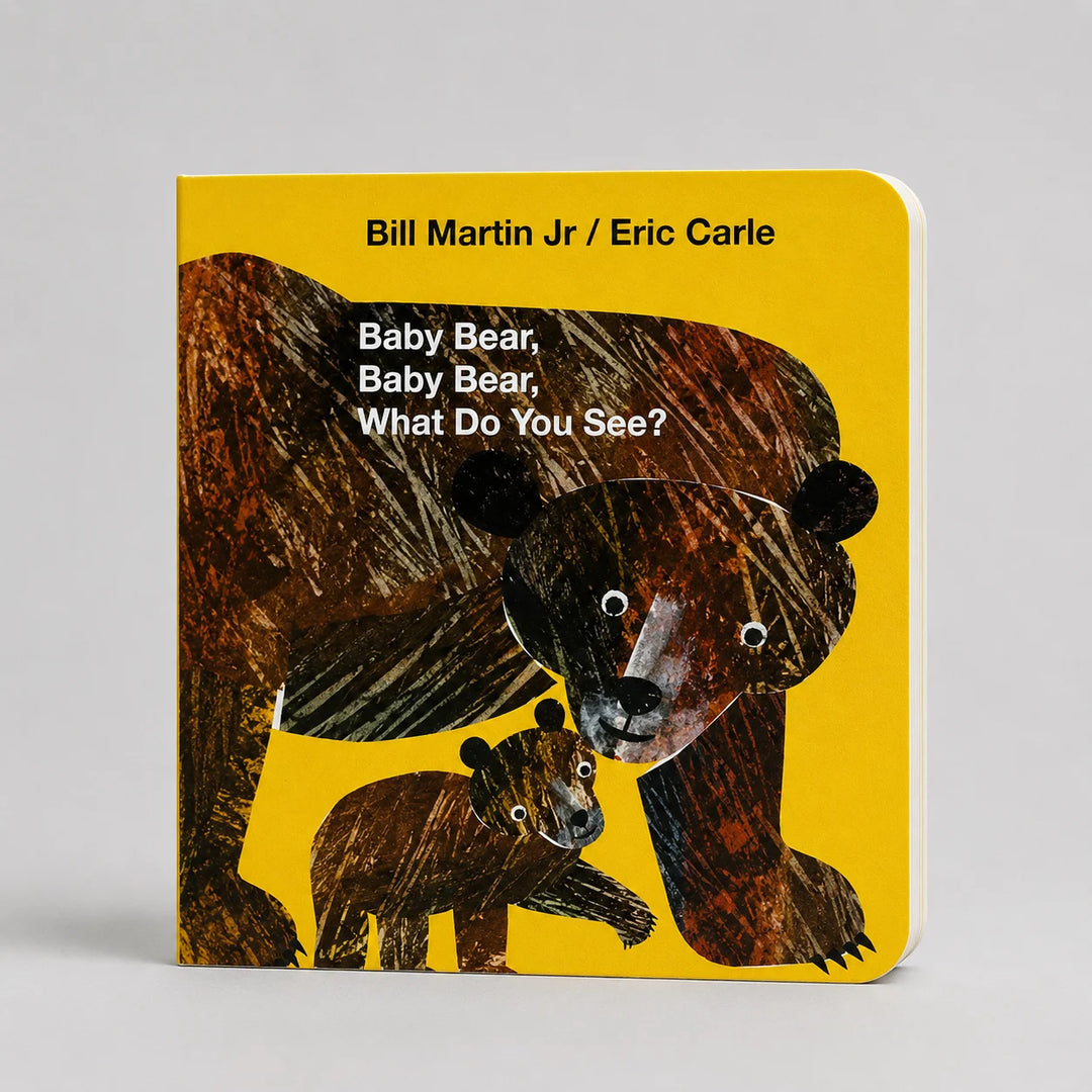 The children's book 'Baby Bear, Baby Bear, What Do You See?' by Bill Martin Jr. and Eric Carle, featuring the classic textured bear illustration on a bright yellow cover, shown standing upright on a neutral gray background.