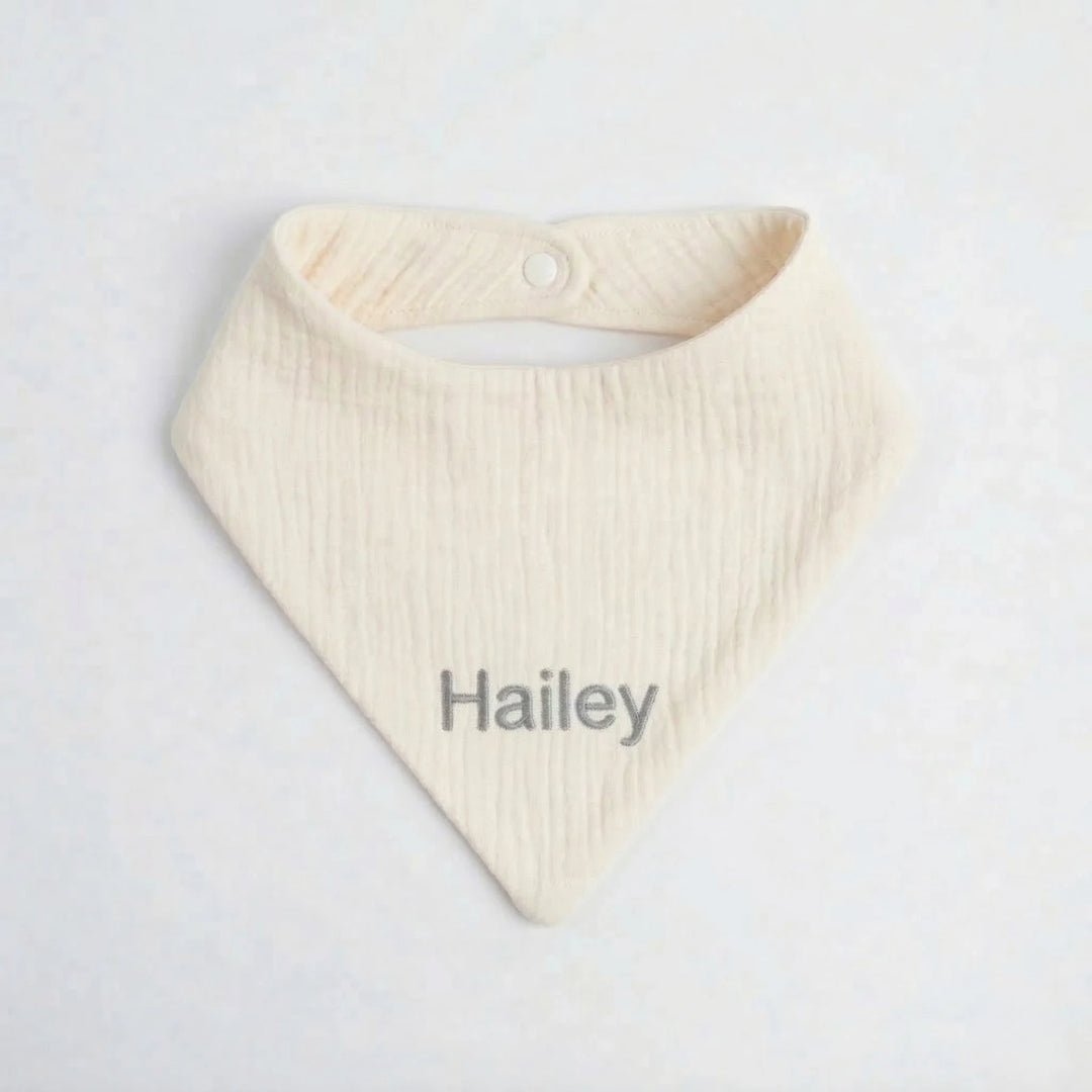 Cream baby bib with 'Hailey' embroidered in Grey thread
