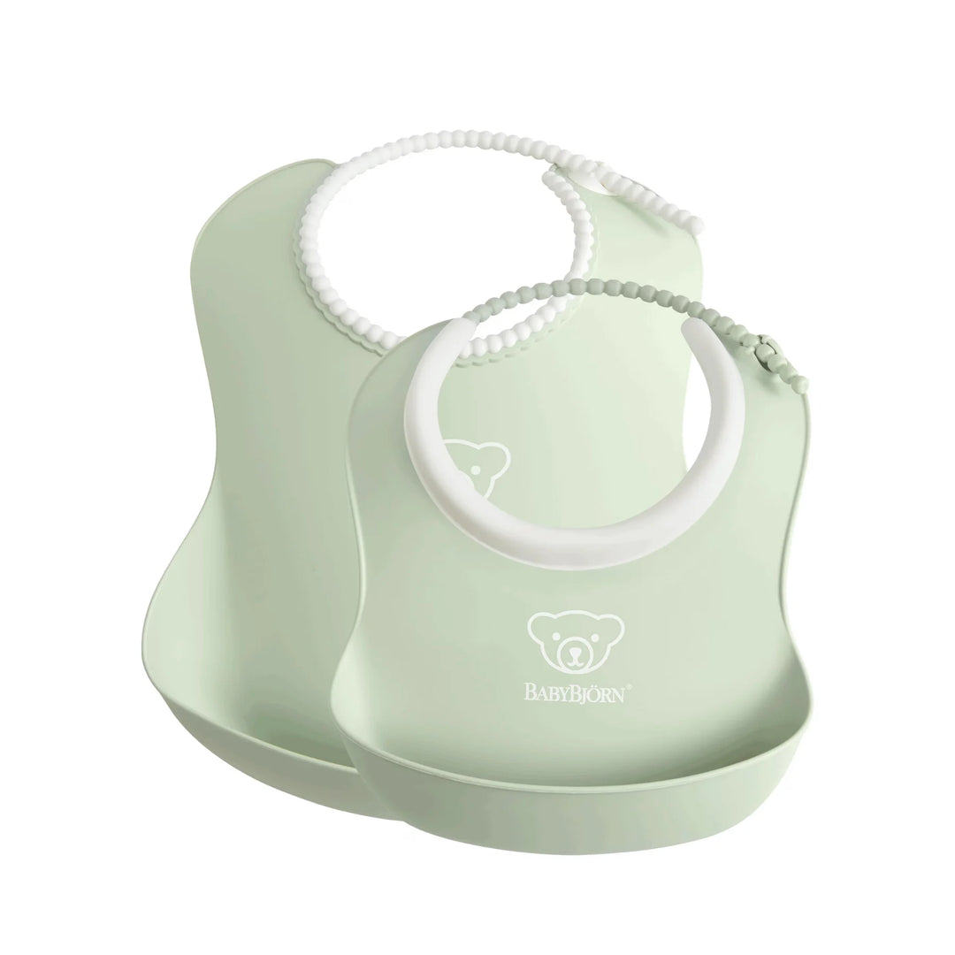Green BabyBjörn 2-pack silicone baby bibs with adjustable neck straps.