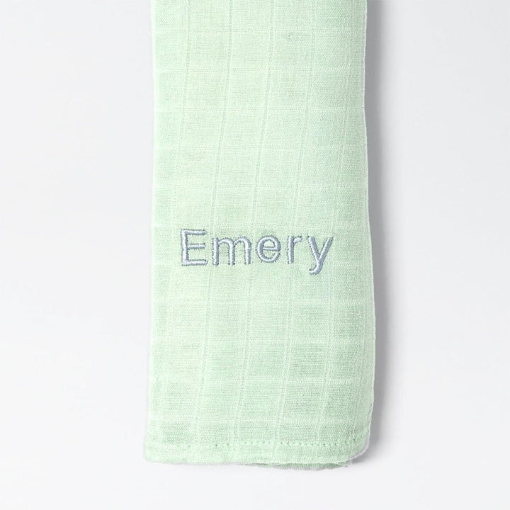 Green bamboo muslin swaddle with "Emery" personalised in grey thread