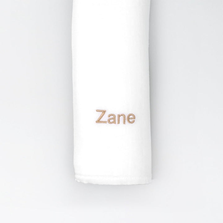 White bamboo muslin swaddle with "Zane" personalised in beige thread