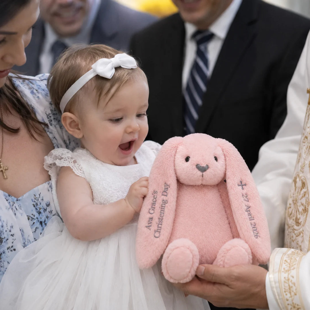 Baby holding a receiving her very own personalised christening day bunny 