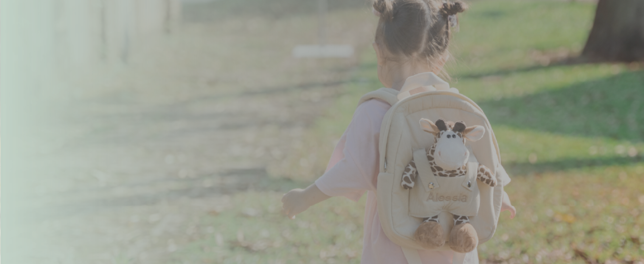 Girl carring giraffe backpack with "Alessia" customised in beige thread