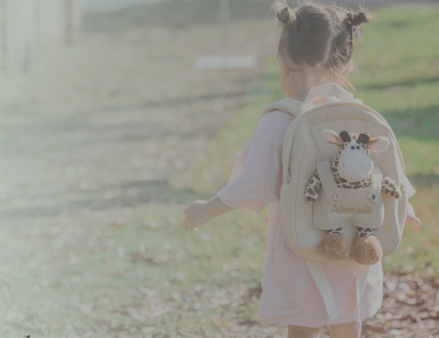 Girl carring giraffe backpack with "Alessia" customised in beige thread