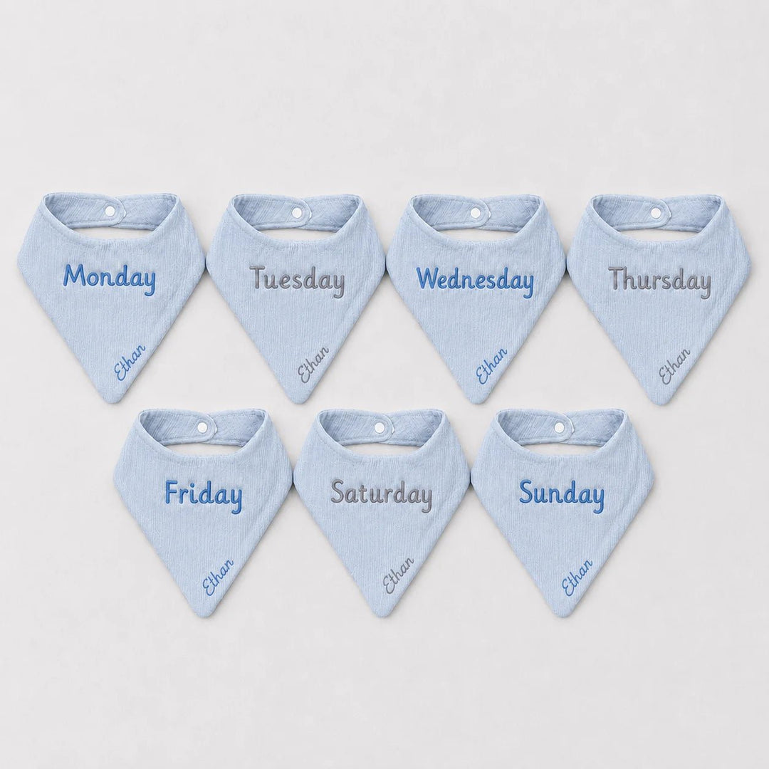 Set of seven blue baby bibs with days of the week embroidery