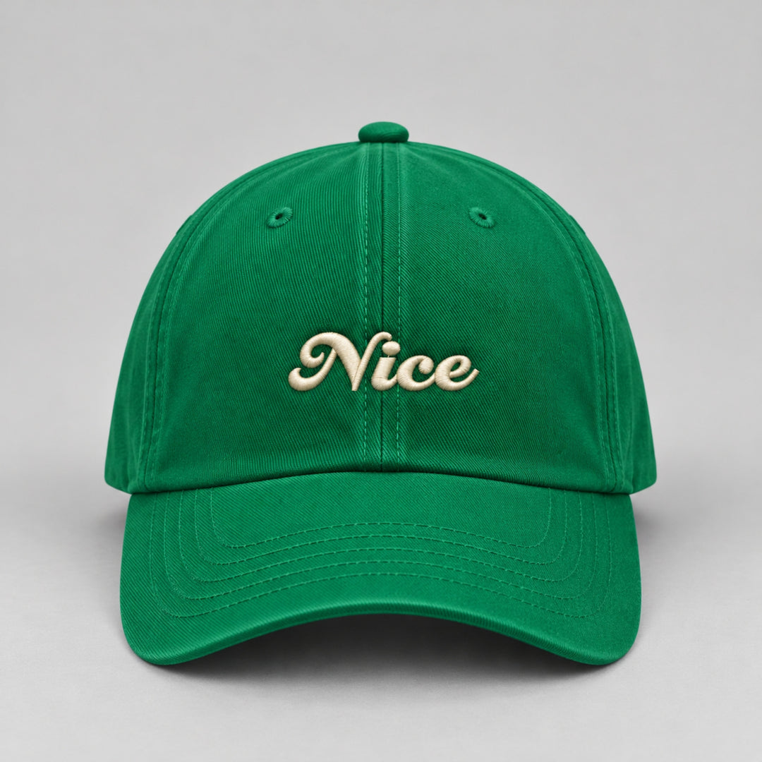 Close-up front view of a vibrant green Christmas baseball cap featuring “Nice” embroidered in cream cursive lettering.