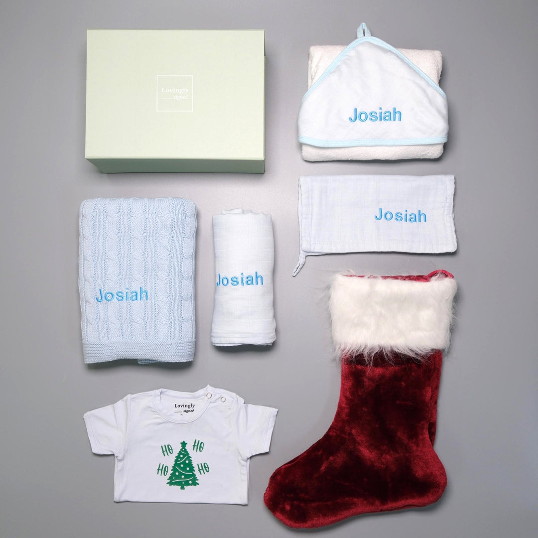 Christmas themed gift set in Blue consisting of hooded towel, muslin cloth, swaddle, cable knit blanket, Christmas edition babygrow and red stocking