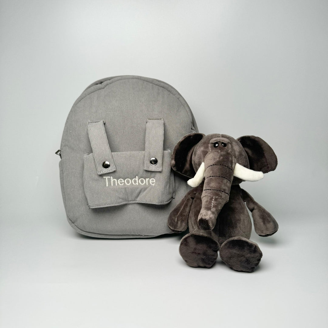 Elephant sitting by a grey backpack with "Theodore" personalised in cream thread