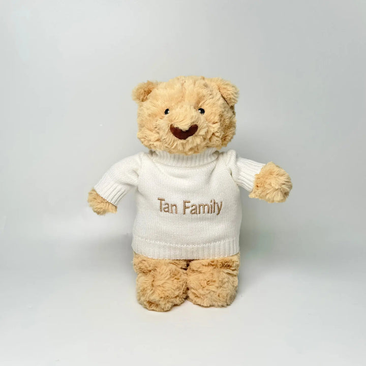 Teddy bear wearing a white sweater with 'Tan Family' personalisation