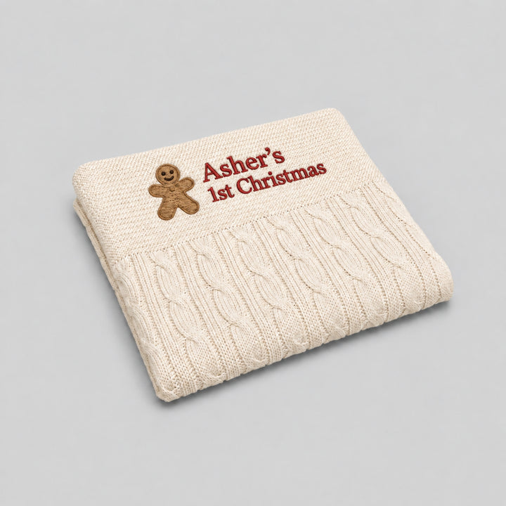 1. Cream cable-knit baby blanket personalised with a gingerbread man motif and “Asher’s 1st Christmas” embroidered in red.