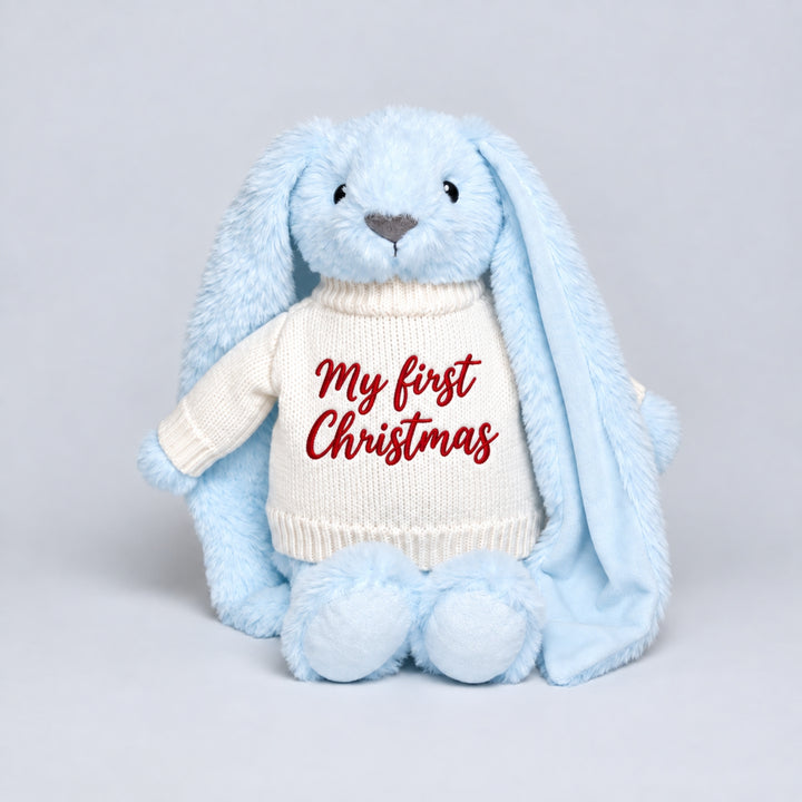 Blue plush bunny with long floppy ears wearing a cream knitted jumper embroidered with “My First Christmas” in red.