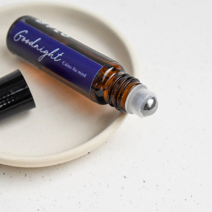 Close-up of Flo Aroma Goodnight essential oil roll-on with metal rollerball applicator and purple label reading “Goodnight – Calms the mind.”