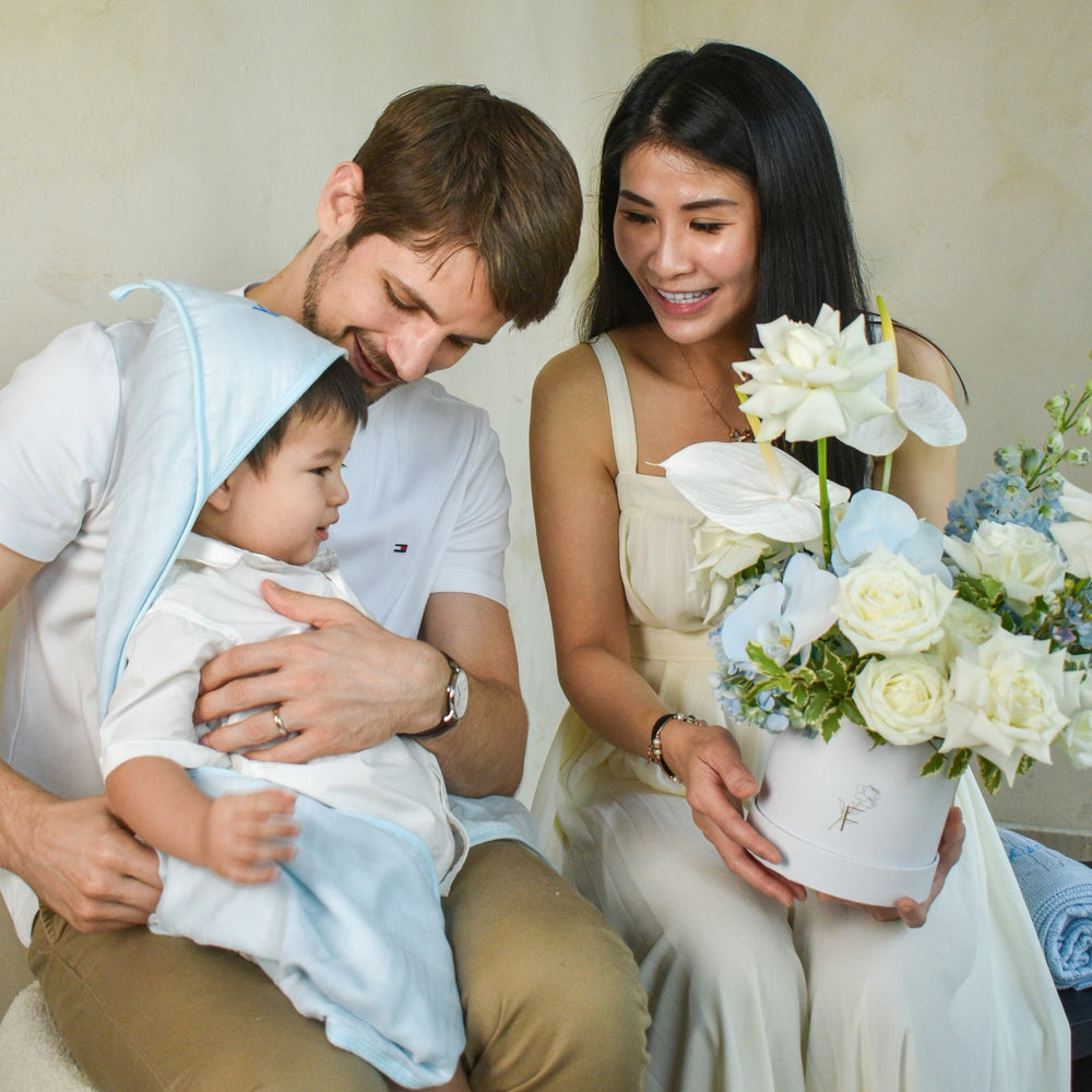 Happy family of 3 - Mum holding flower bloom box from The Florté and little one in hooded towel from Lovingly Signed.