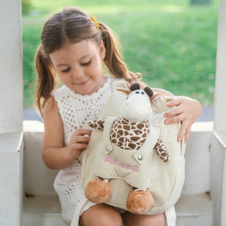 Girl and her giraffe backpack with "Ariana" personalised in pink thread