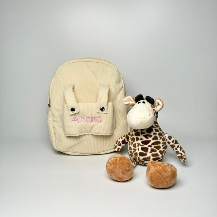 Giraffe sitting by cream backpack with "Ariana" personalised in pink thread