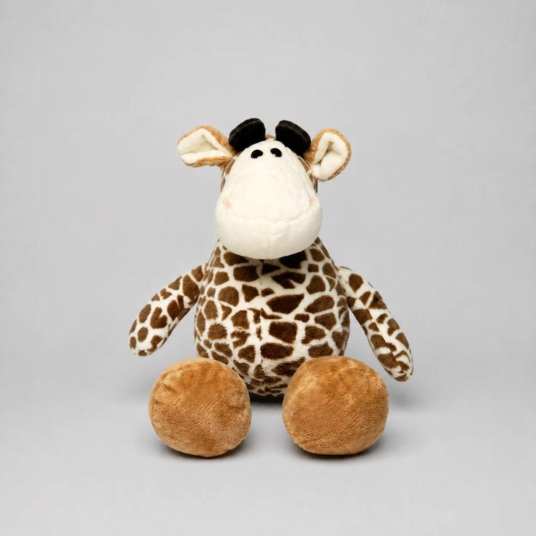 A plush giraffe toy with a brown and beige patterned body, a cream-colored snout and ears, and round tan feet, photographed against a plain light gray studio background.