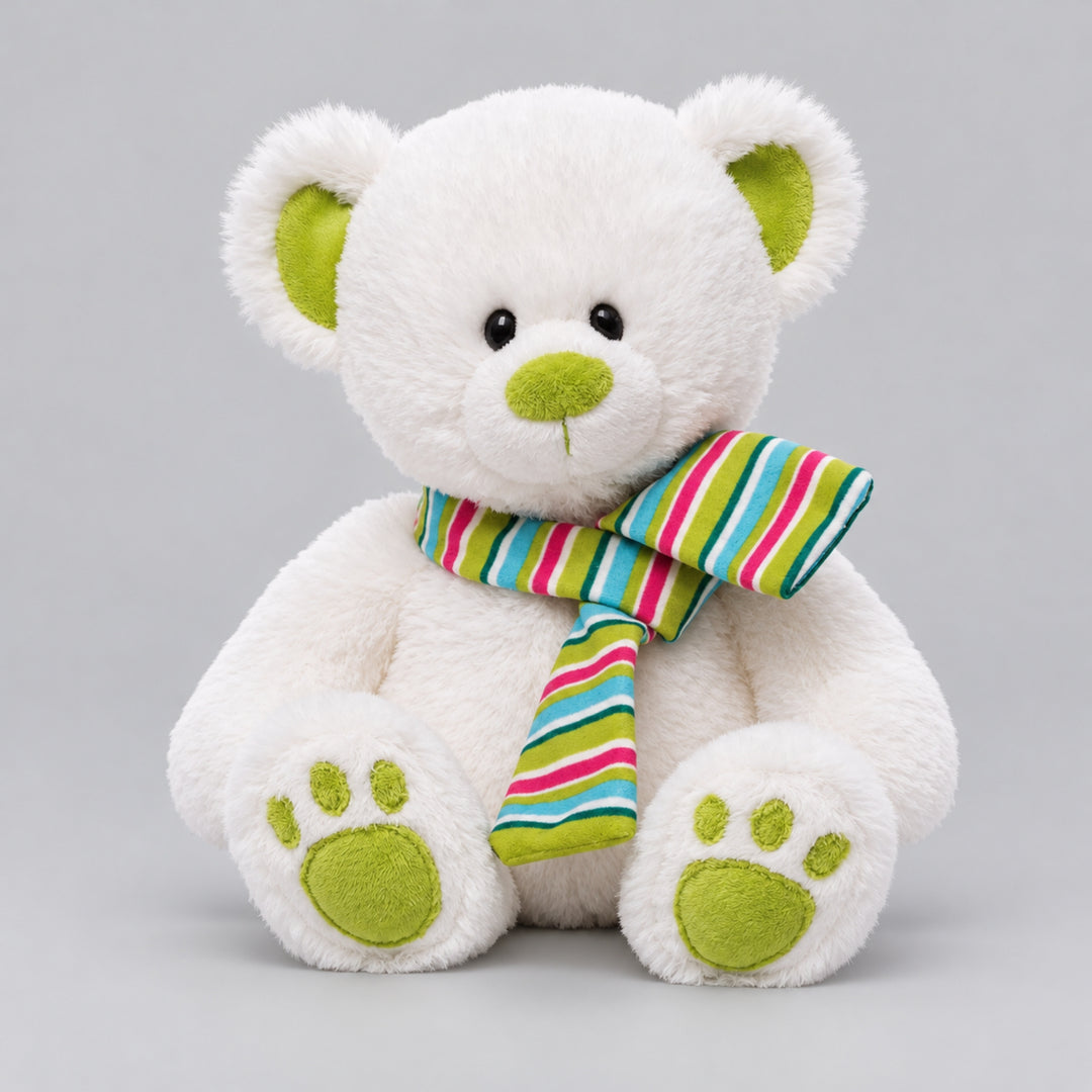 White teddy bear with bright green inner ears, nose and paw pads, wearing a colourful striped scarf against a light grey studio background.