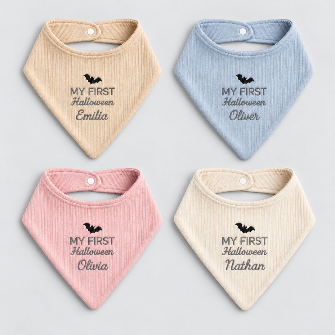 Four personalised Halloween baby bandana bibs in beige, blue, pink and cream, arranged in a 2×2 layout with embroidered bats, “My First Halloween” lettering and individual names.