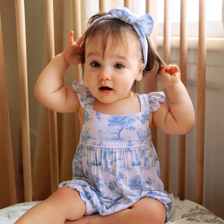 Baby wearing House of Holly Garden Toile Ruffle Bubble Romper in Blue