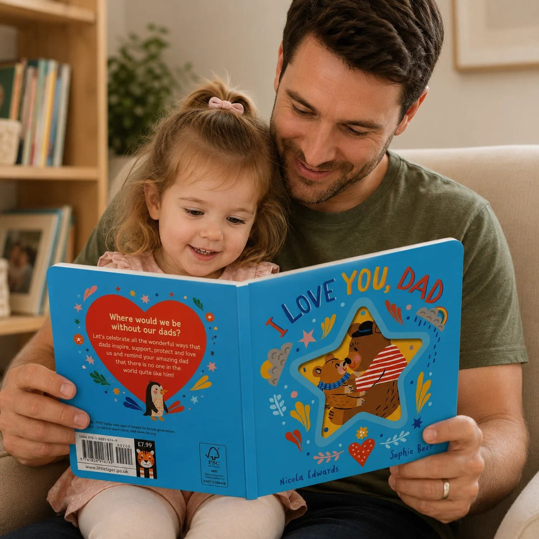 FAther and child reading a book together titled 'I Love You, Dad' in a cosy living room.