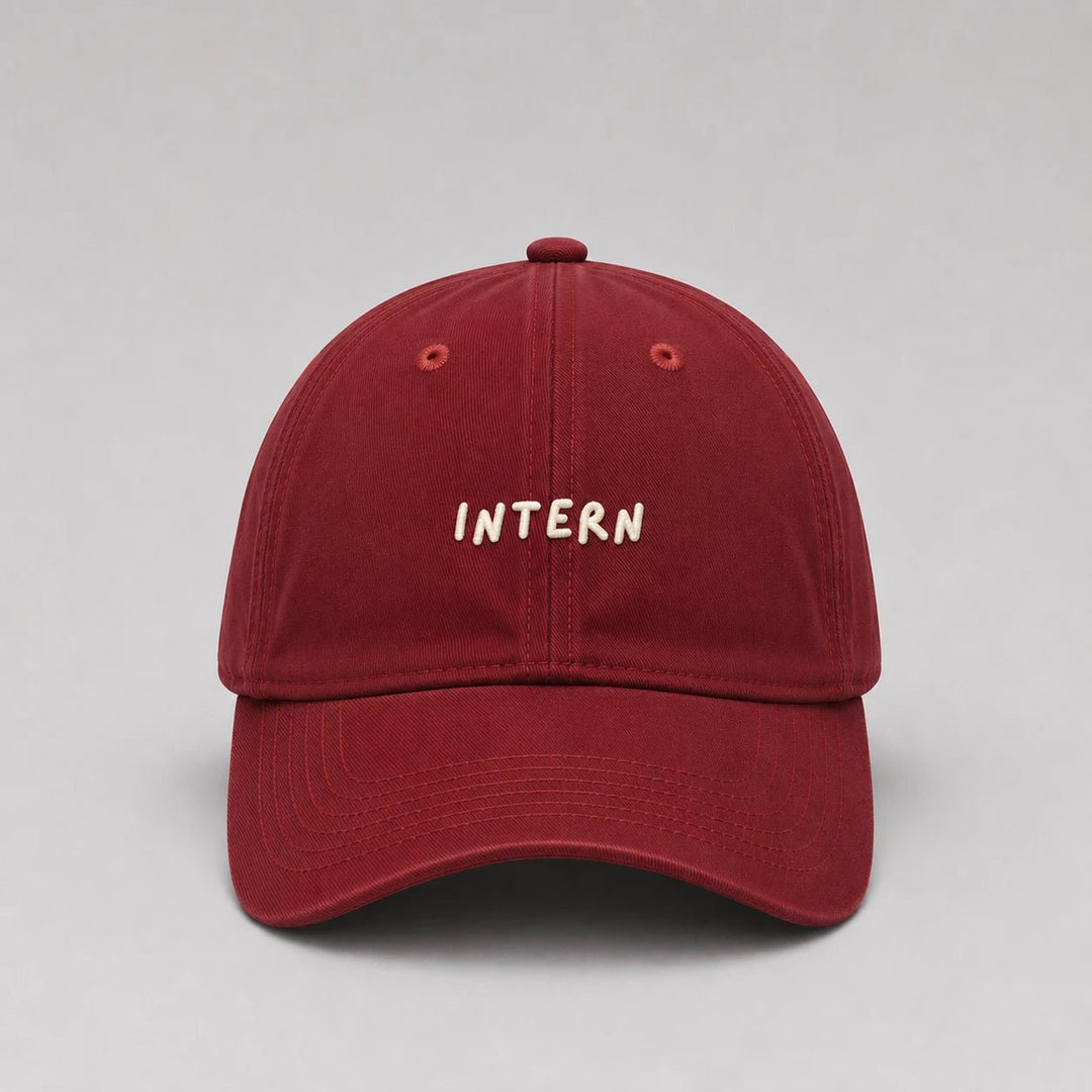 Red cap with 'INTERN' embroidered on a gray background