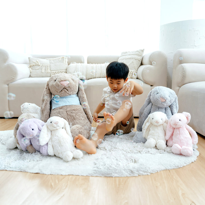 Child playing with bubbles, surrounded by Jellycat bunnies