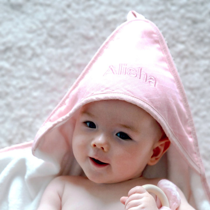 The hood of the towel is large, creating a playful, oversized look on the baby