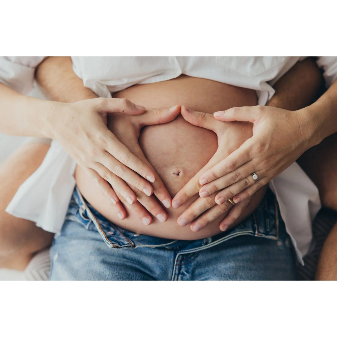 New parents holding hands in a heart shape over a pregnant belly, magical maternity shoot photographed by Katie Martin-Sperry Photography