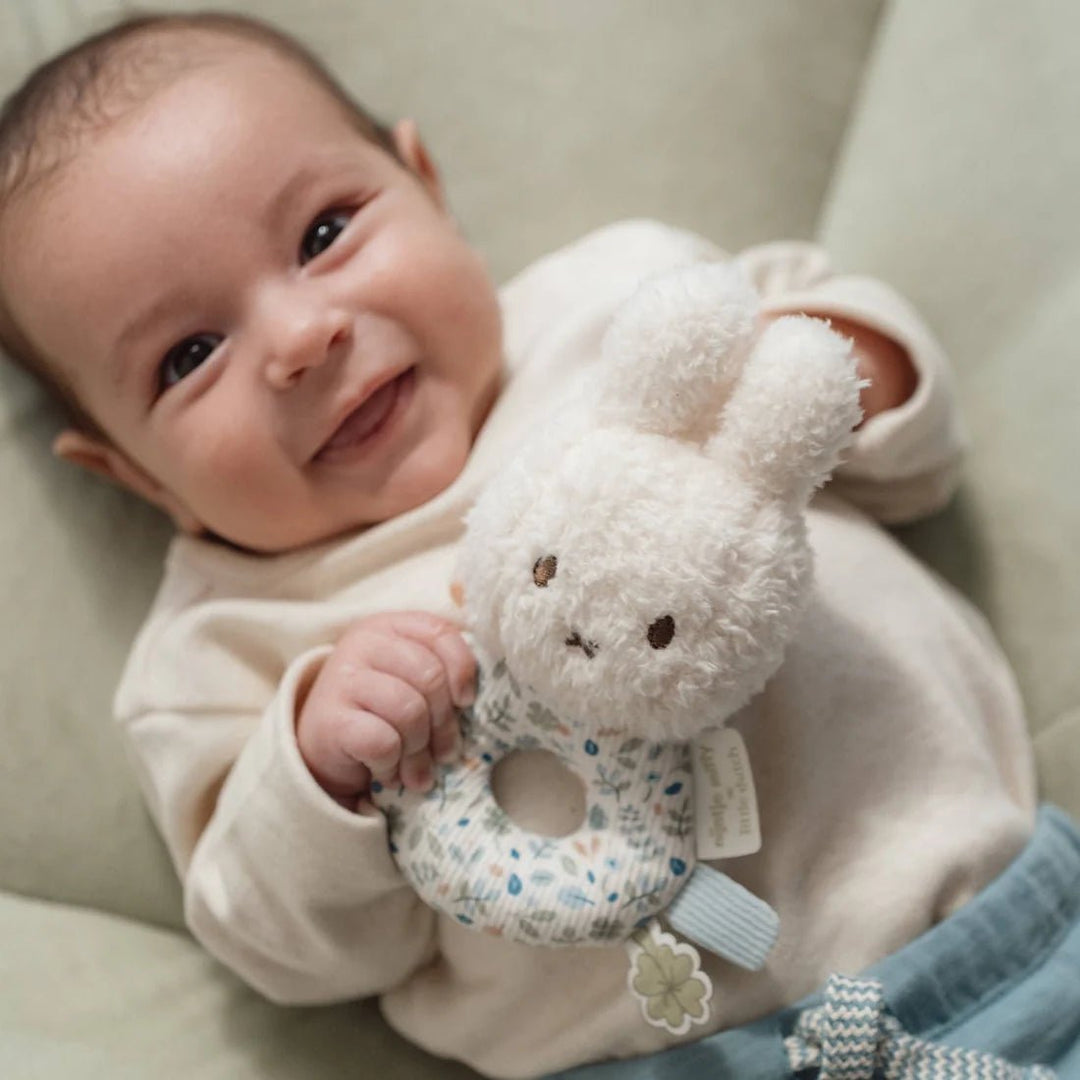 Baby holding Miffy x Little Dutch Rattle - Lucky Leaves with a neutral background
