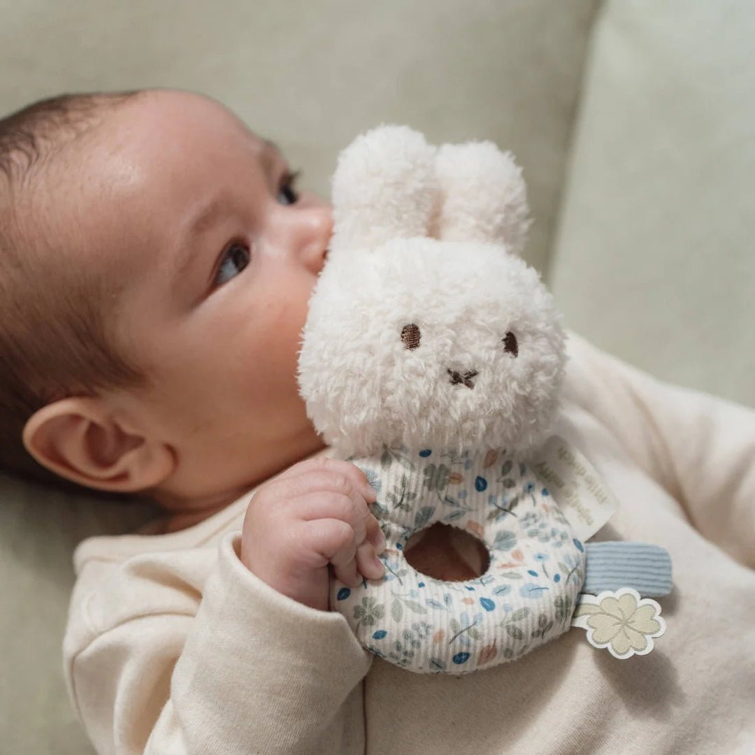 Baby holding a Miffy x Little Dutch Rattle - Lucky Leaves with a neutral background